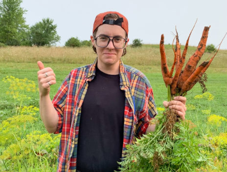 Resident artist Madigan Burke, 2021 Wormfarm Artist Resident is harvesting a large bunch of carrots.